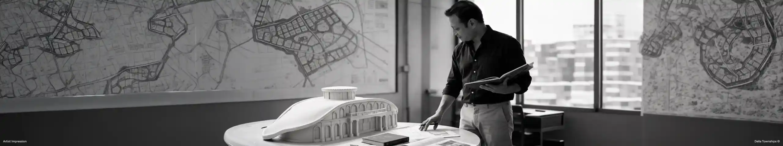 Architect studying architectural models and masterplan drawings to explore future living environments by Della Townships India